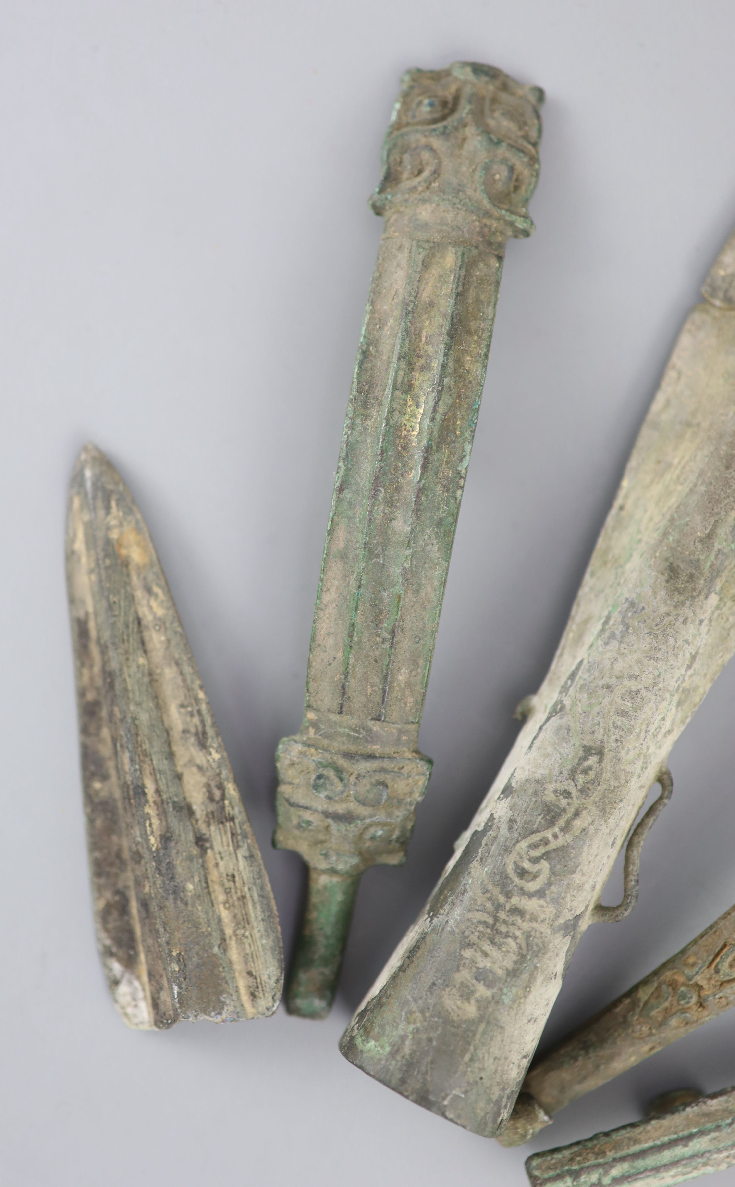 Three Chinese archaic bronze belt hooks and two spear heads, Warring States / Han dynasty